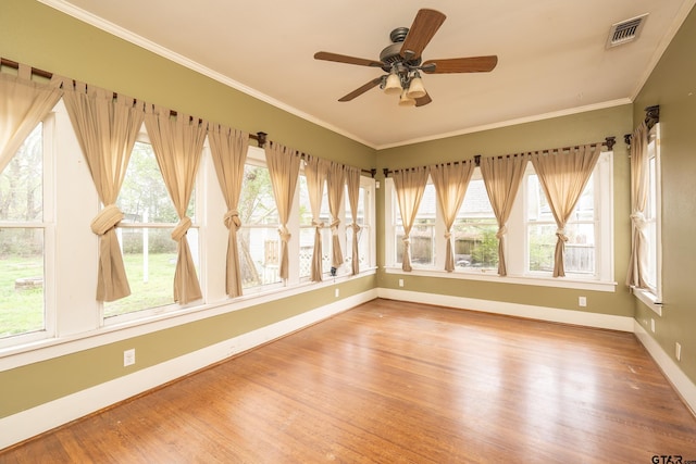 unfurnished sunroom featuring baseboards, visible vents, wood finished floors, and ornamental molding