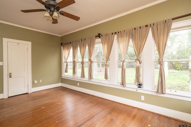 unfurnished room with baseboards, a ceiling fan, wood finished floors, and crown molding