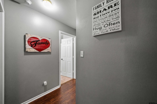 hallway featuring baseboards and wood finished floors