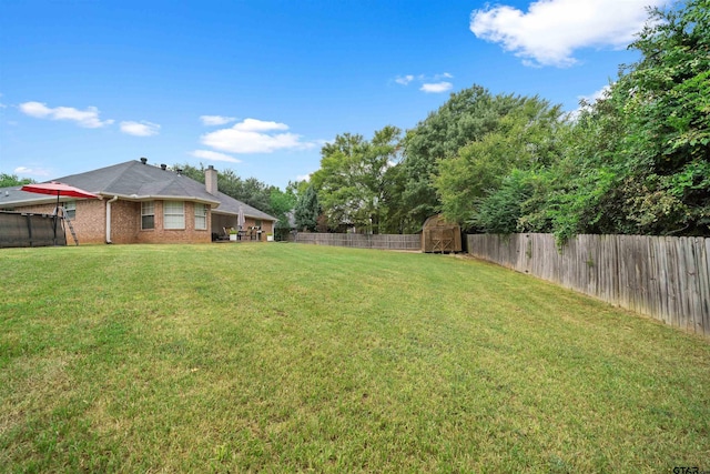 view of yard with an outbuilding, a storage unit, and a fenced backyard