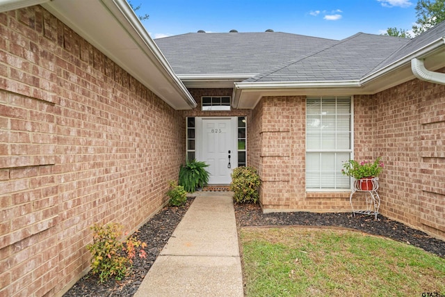 property entrance featuring brick siding and roof with shingles