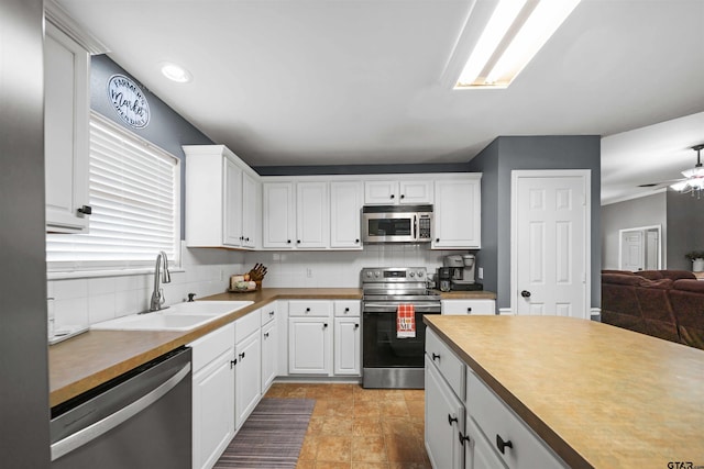 kitchen with a sink, tasteful backsplash, appliances with stainless steel finishes, and white cabinets