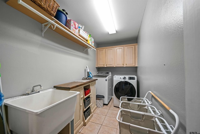 laundry room with light tile patterned floors, washing machine and dryer, cabinet space, and a sink