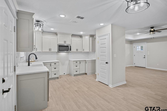 kitchen featuring white cabinetry, decorative light fixtures, sink, light hardwood / wood-style floors, and ceiling fan