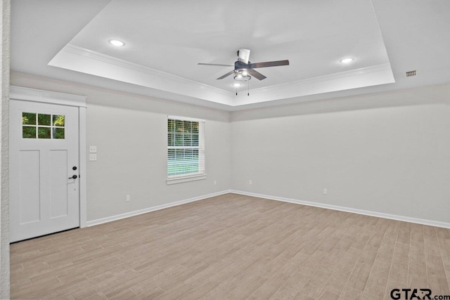 interior space with a wealth of natural light, a tray ceiling, and light hardwood / wood-style flooring