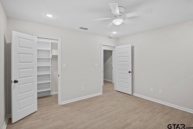 unfurnished bedroom with light hardwood / wood-style flooring, ceiling fan, a spacious closet, and a closet