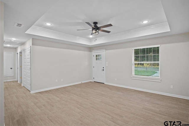 unfurnished room featuring light hardwood / wood-style flooring, ornamental molding, and a raised ceiling