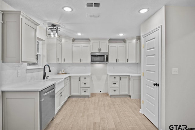 kitchen with light hardwood / wood-style flooring, white cabinetry, backsplash, and stainless steel appliances