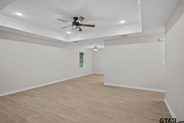 unfurnished room with light wood-type flooring, a tray ceiling, ceiling fan, and ornamental molding