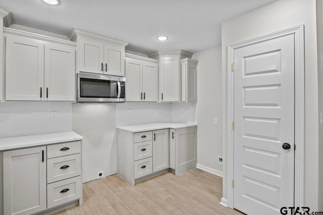 kitchen featuring backsplash, white cabinets, and light hardwood / wood-style flooring