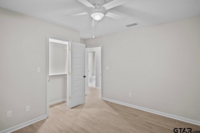 unfurnished bedroom with ceiling fan, a closet, light wood-type flooring, and a spacious closet