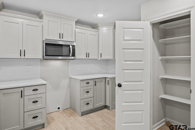 kitchen featuring white cabinets, light hardwood / wood-style floors, and tasteful backsplash