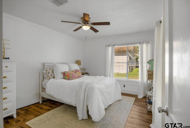 bedroom with wood finished floors, crown molding, and a ceiling fan