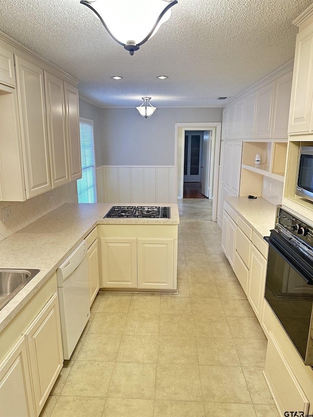 kitchen featuring a textured ceiling, appliances with stainless steel finishes, and kitchen peninsula