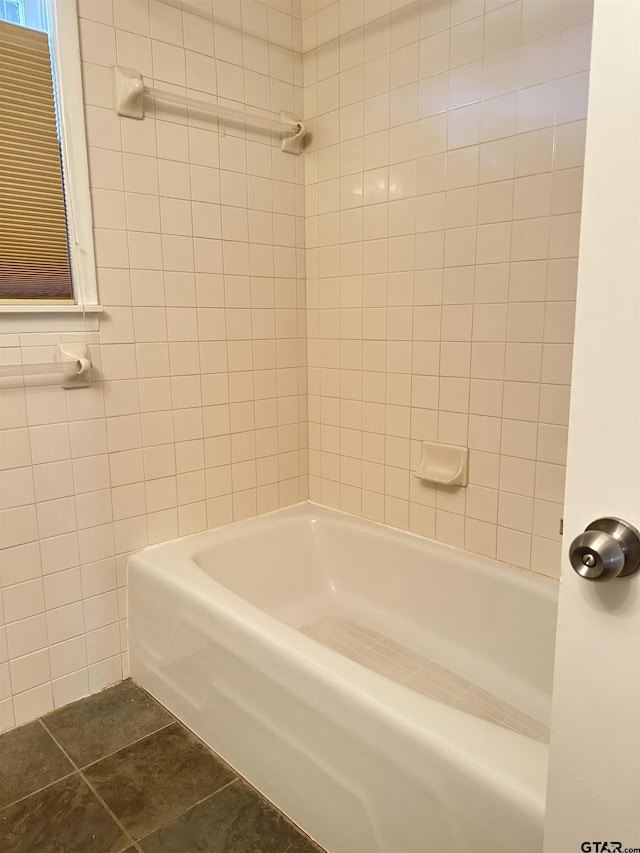 bathroom with tile walls, tiled shower / bath combo, and tile patterned flooring