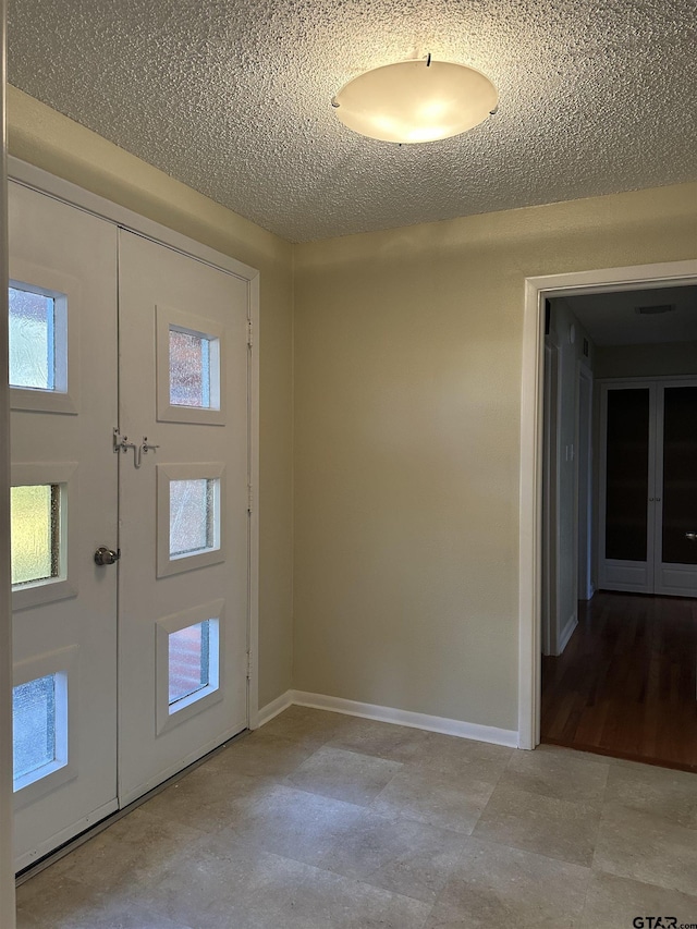 foyer entrance with french doors and a textured ceiling