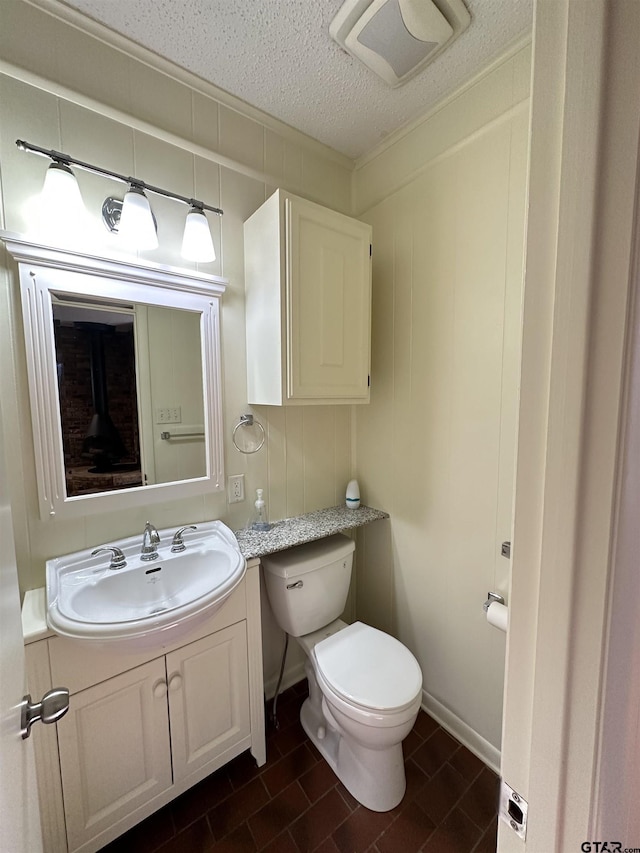 bathroom featuring a textured ceiling, toilet, and vanity