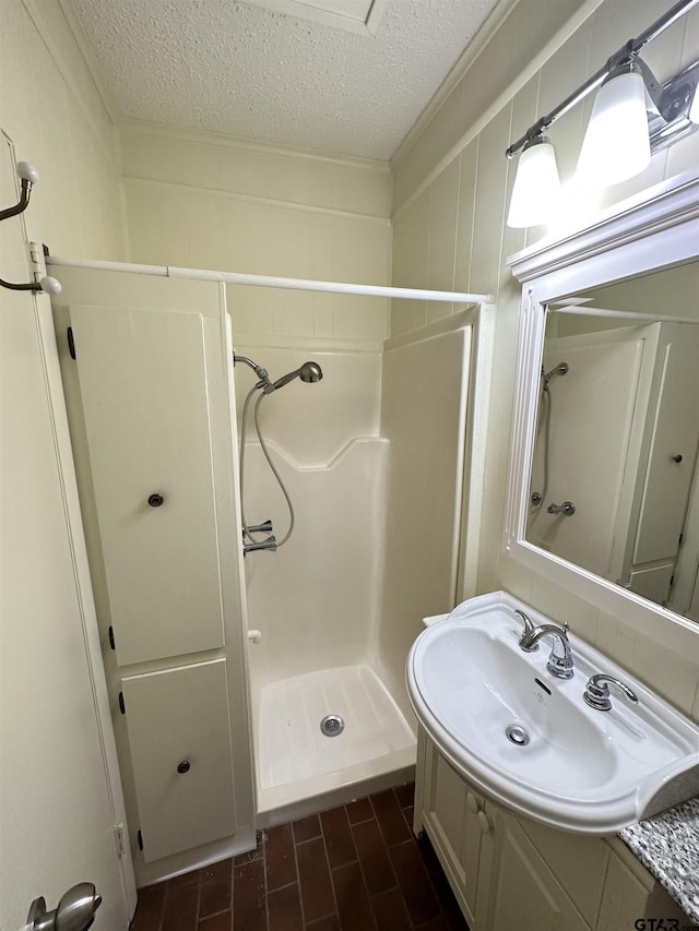 bathroom featuring a textured ceiling, walk in shower, and vanity