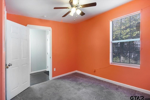 empty room with ceiling fan and dark carpet