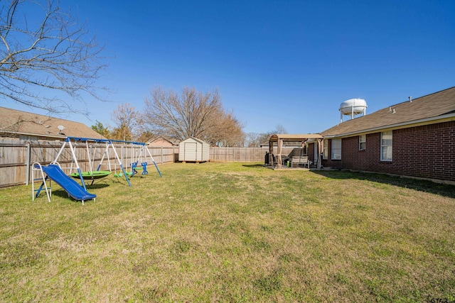 view of yard featuring an outbuilding, a fenced backyard, a playground, and a storage shed