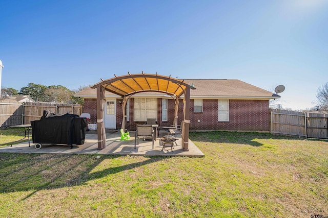 back of house featuring a patio, brick siding, a lawn, and a fenced backyard