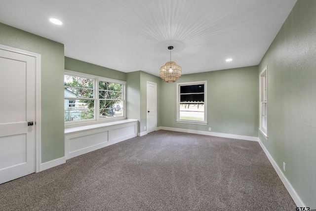 carpeted spare room with a notable chandelier