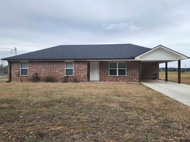 single story home with a shingled roof, a front yard, an attached carport, and brick siding