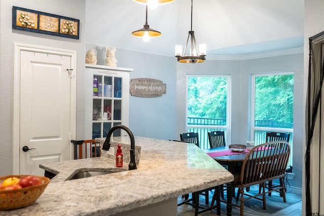 interior space with a notable chandelier, light stone countertops, wood finished floors, a sink, and hanging light fixtures