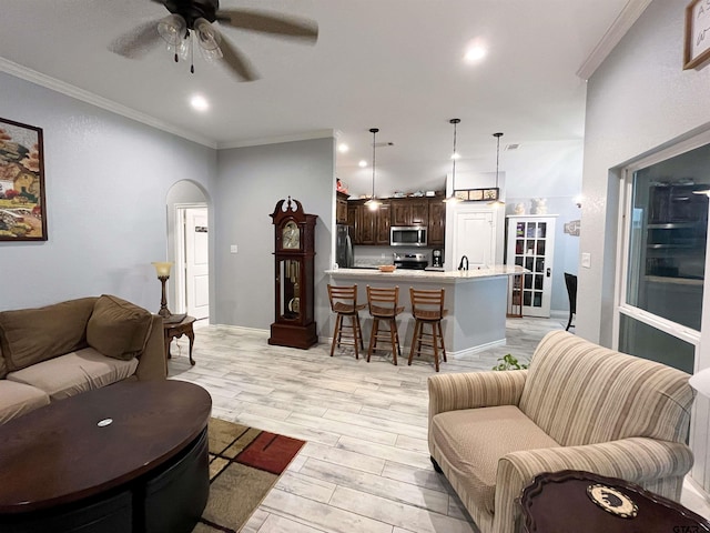 living room with recessed lighting, crown molding, light wood-style floors, ceiling fan, and arched walkways