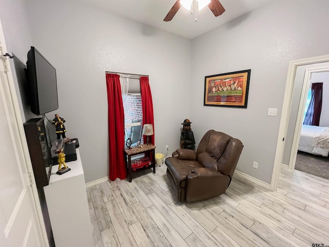 living area with ceiling fan, light wood finished floors, and baseboards