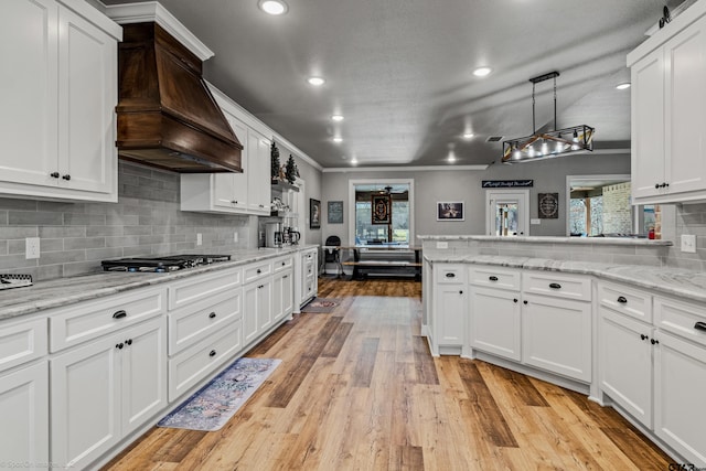 kitchen with premium range hood, white cabinetry, and stainless steel gas cooktop