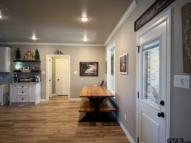 dining area featuring ornamental molding, a wealth of natural light, and light hardwood / wood-style flooring