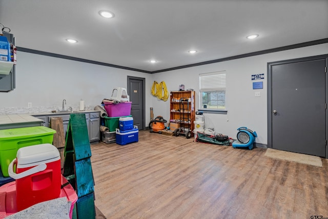 rec room with sink, light hardwood / wood-style floors, and ornamental molding