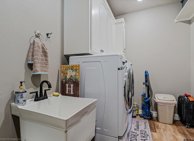 laundry room featuring separate washer and dryer, sink, cabinets, and light hardwood / wood-style floors