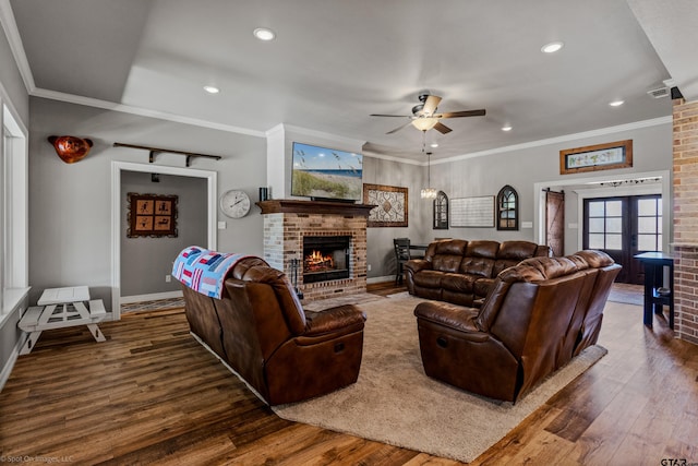 living room with ceiling fan, french doors, dark wood-type flooring, a brick fireplace, and ornamental molding