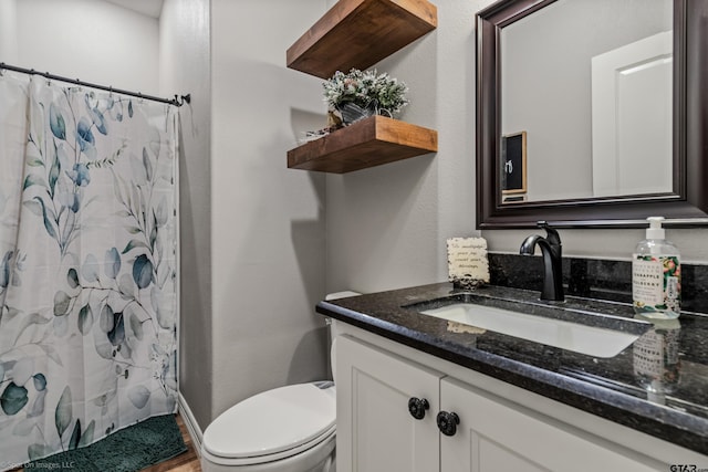 bathroom with toilet, vanity, and walk in shower