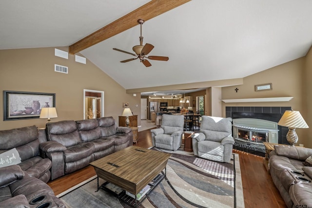 living room featuring vaulted ceiling with beams, ceiling fan, hardwood / wood-style floors, and a fireplace