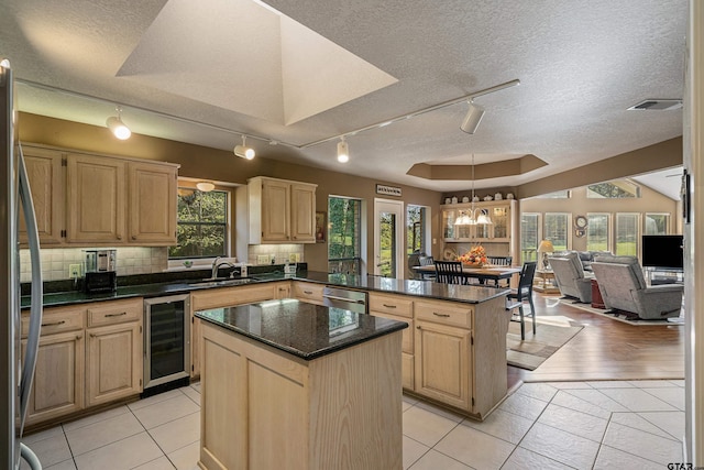 kitchen featuring a textured ceiling, a center island, light tile patterned floors, and beverage cooler