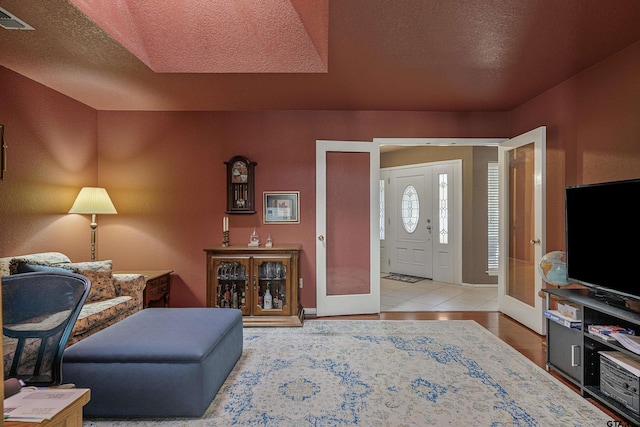 foyer featuring french doors, a textured ceiling, and tile patterned flooring