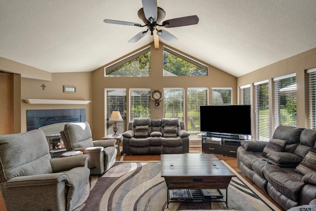 256 Ox Bow Cv, Holly Lake Ranch, TX 75765 - living area featuring vaulted ceiling, a ceiling fan, plenty of natural light, a tiled fireplace, and a textured ceiling