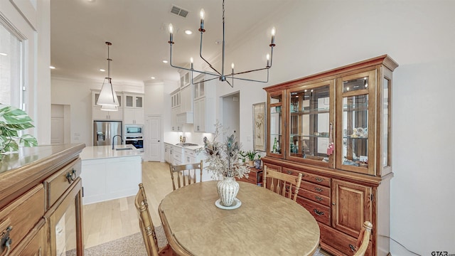 9070 Shallow Cv, Tyler, TX 75703 - dining area featuring crown molding, light wood-style floors, a chandelier, and a high ceiling
