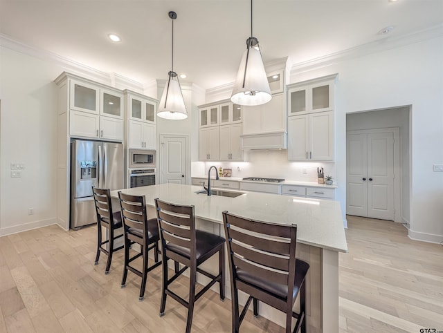 9070 Shallow Cv, Tyler, TX 75703 - kitchen featuring crown molding, stainless steel appliances, light wood-style flooring, a kitchen breakfast bar, and a center island with sink