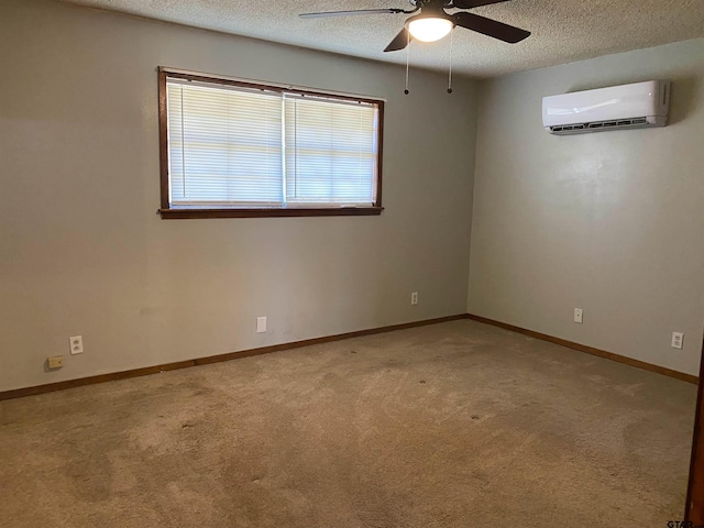 empty room featuring carpet floors, an AC wall unit, a textured ceiling, and baseboards