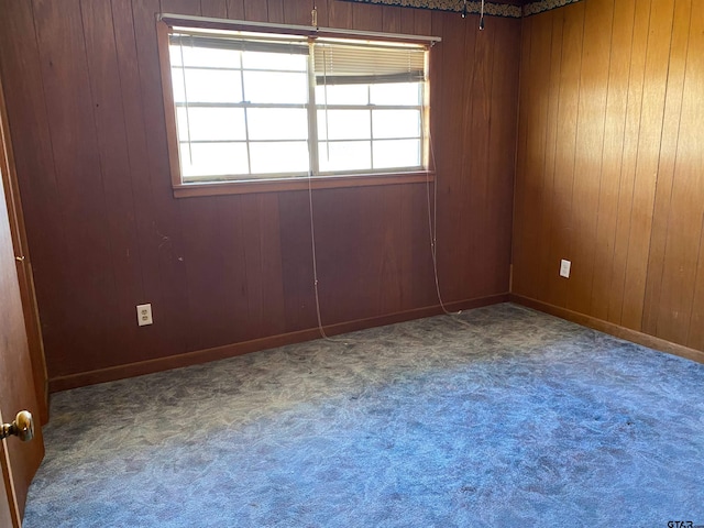 carpeted spare room with wooden walls