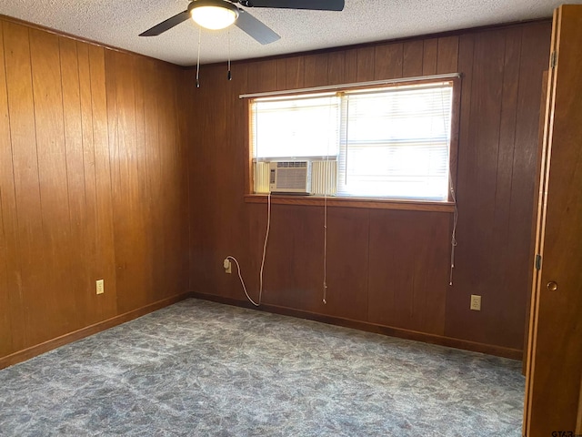 carpeted spare room with a textured ceiling, cooling unit, and wooden walls