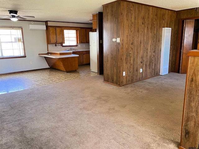 kitchen with light carpet, wooden walls, open floor plan, and freestanding refrigerator