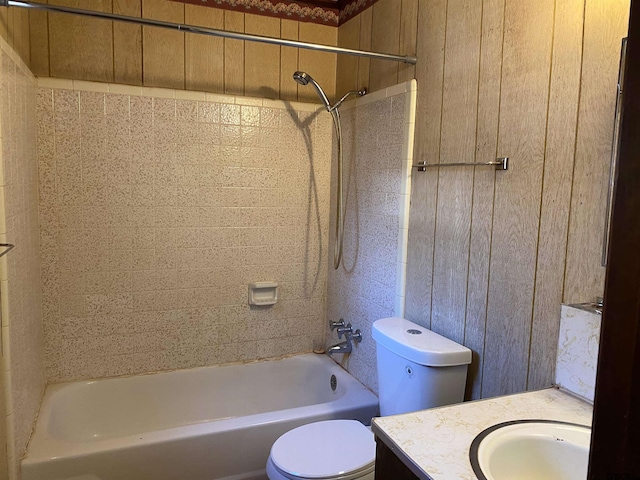 full bathroom featuring toilet, wood walls, bathtub / shower combination, and vanity