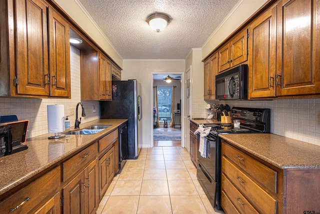 kitchen featuring sink, crown molding, light tile patterned floors, stone counters, and black appliances