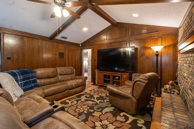 living room with vaulted ceiling with beams, a textured ceiling, wooden walls, ceiling fan, and hardwood / wood-style floors