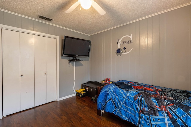 bedroom featuring a textured ceiling, ornamental molding, dark hardwood / wood-style floors, a closet, and ceiling fan